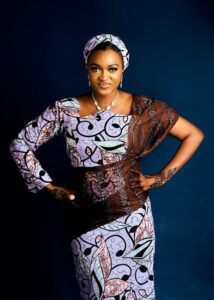 Confident woman in colorful traditional African dress poses against a blue backdrop.